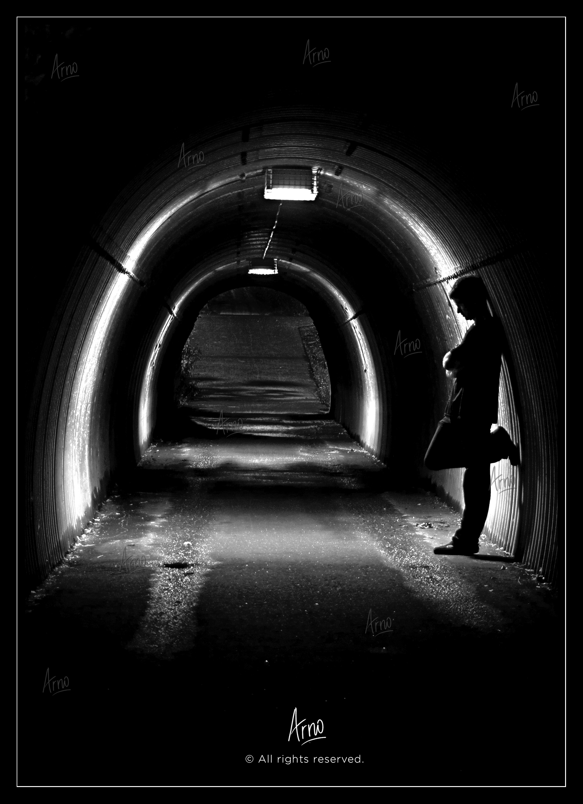 Young man standing in a dark tunnel